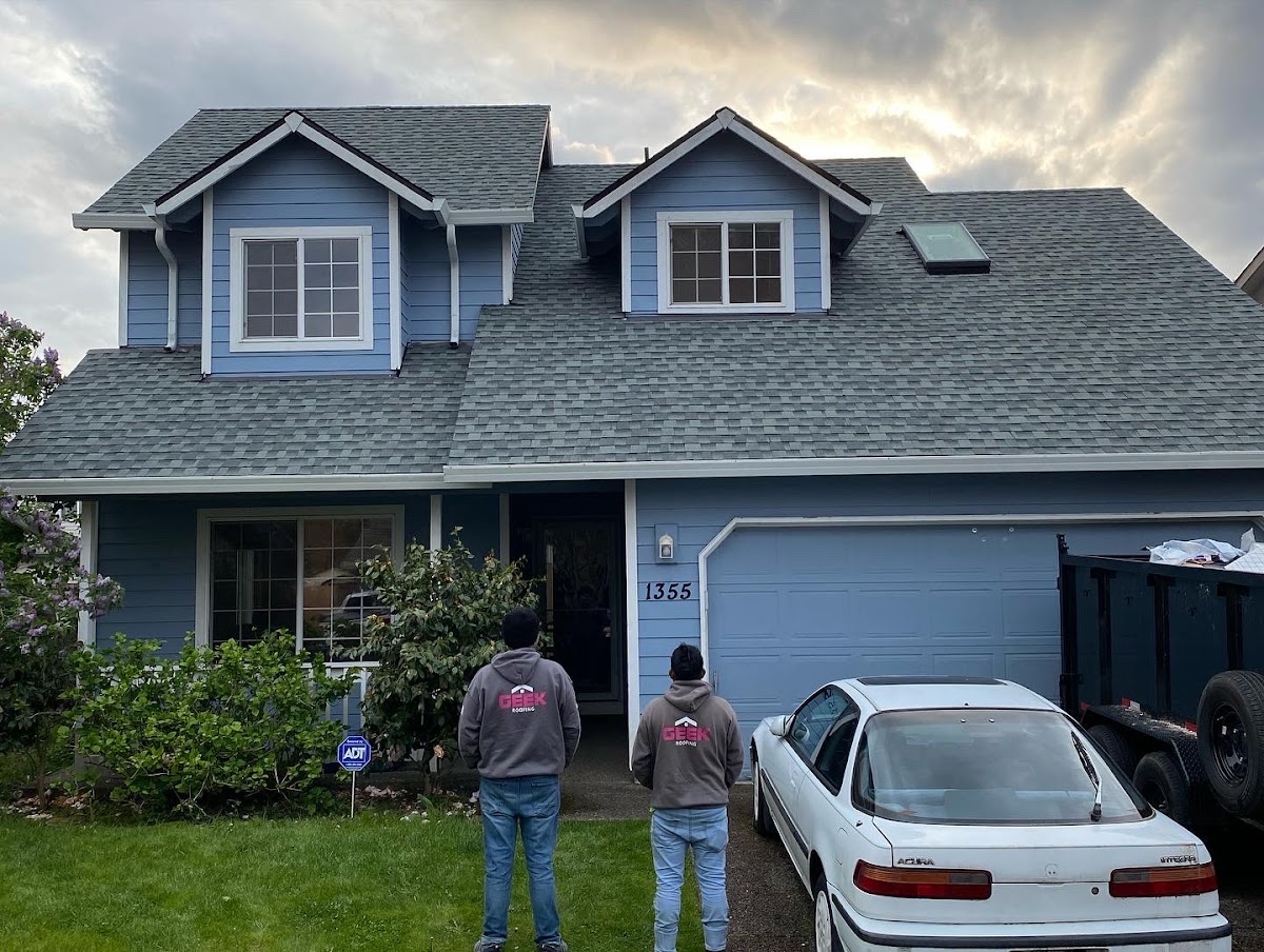 Geek Roofing crew in branded jackets in front of a completed job