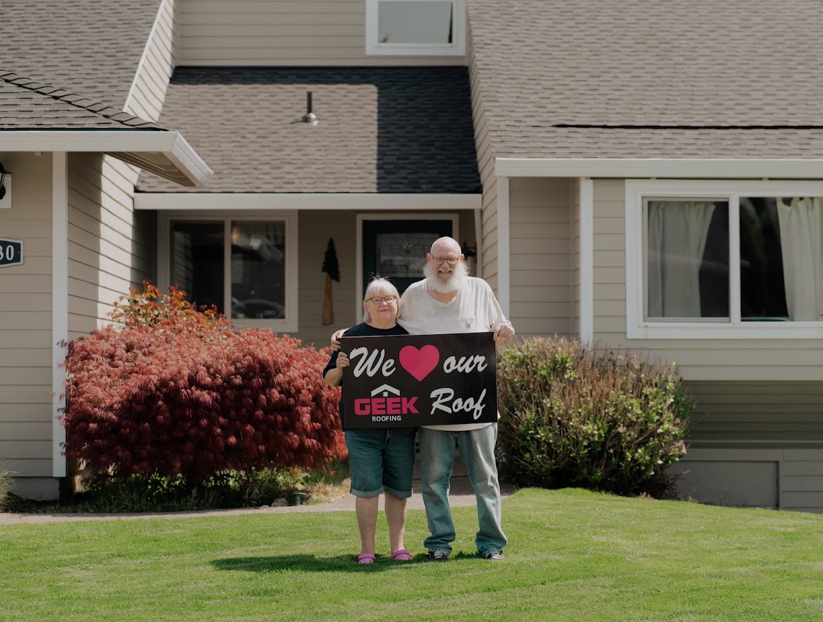 Homeowners holding a we love our roof sign